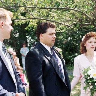 Wedding ceremony with bride, groom, officiant, and guests outdoors.
