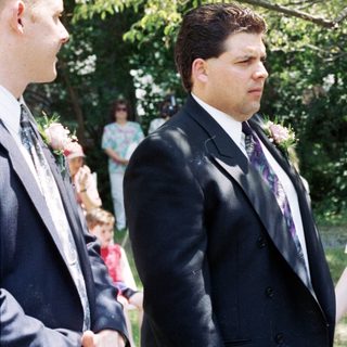 Wedding ceremony with bride, groom, officiant, and guests outdoors.