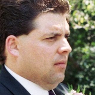 Wedding ceremony with bride, groom, officiant, and guests outdoors.