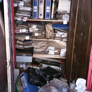 Cluttered cabinet filled with old files and miscellaneous items.