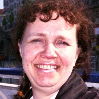 Woman smiling near waterfront restaurant building.