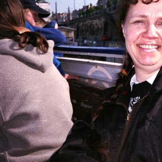 Woman smiling near waterfront restaurant building.