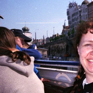 Woman smiling near waterfront restaurant building.