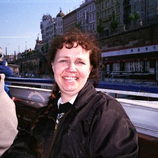 Woman smiling near waterfront restaurant building.