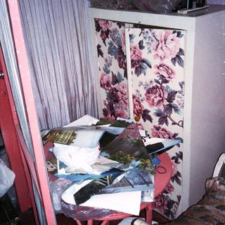 Cluttered vintage storage cabinet with floral pattern.