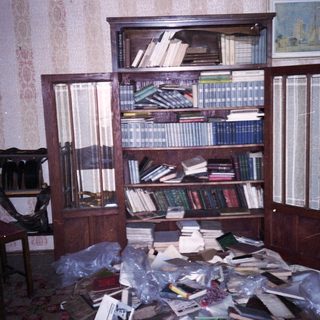 Overcrowded room with bookshelves and scattered books.