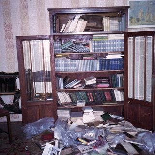 Overcrowded room with bookshelves and scattered books.