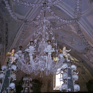 Elaborate chandelier with angelic figures and skull decorations.