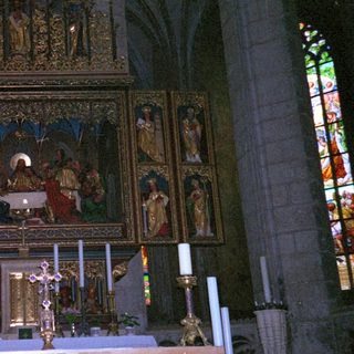 Gothic cathedral altar with religious artwork and candles.