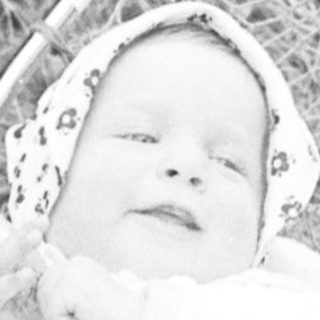 Baby in vintage pram on grassy path.
