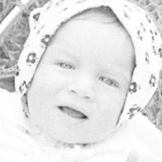 Baby in vintage pram outdoors, smiling.