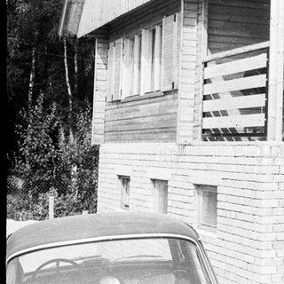 Family posing on balcony of wooden house.