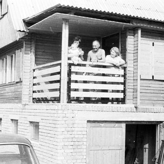 Family posing on balcony of wooden house.