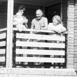 Family posing on balcony of wooden house.