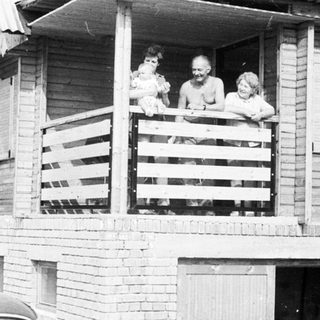 Family posing on balcony of wooden house.