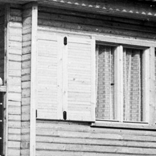 Family posing on balcony of wooden house.