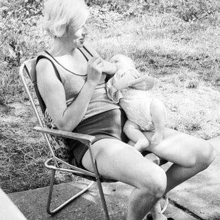 Woman holding small dog in outdoor chair.