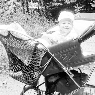 Baby in vintage stroller on forest path.
