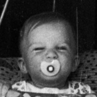 Baby suspended in hanging seat indoors.