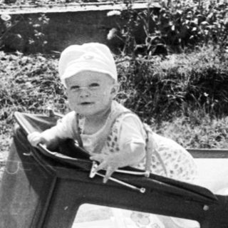 Baby sitting in vintage pram outdoors.