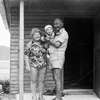 Family posing with baby on porch near lake.