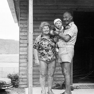 Family posing with baby on porch near lake.