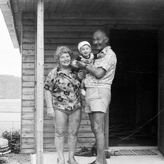 Family posing with baby on porch near lake.