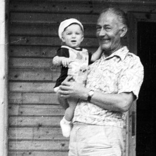 Older man holding young child outdoors.