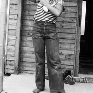 A woman holding a baby outside a wooden shed.