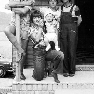 Family posing together outdoors near a rustic building.