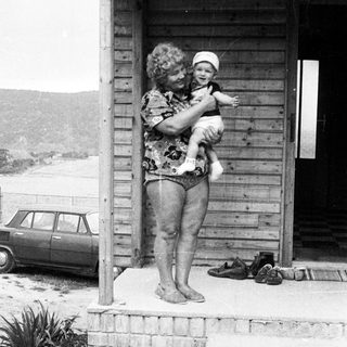 A woman holds a baby on a porch.