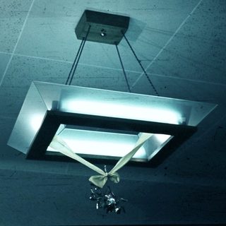 Industrial ceiling light fixture with hanging decorative element.