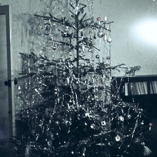 Vintage Christmas tree with metallic ornaments indoors.