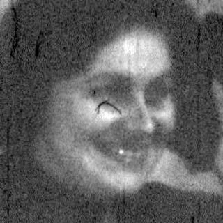 Blurry reflection of person sitting indoors.