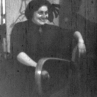 Blurry reflection of person sitting indoors.