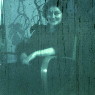Blurred reflection of person sitting on window ledge.
