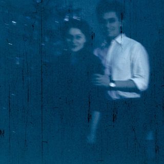 Reflection of two people indoors near window.