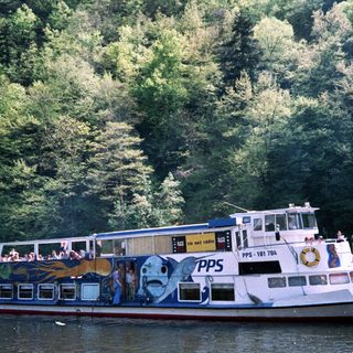 Passenger boat cruising through forested river.