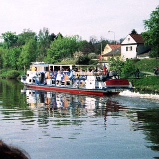 Scenic river with passenger boat and people observing.