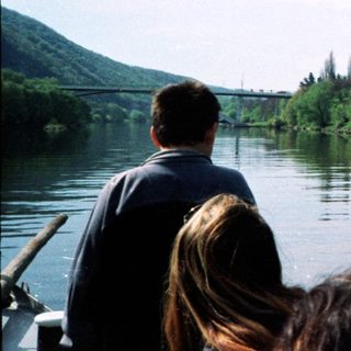 Scenic river with passenger boat and people observing.