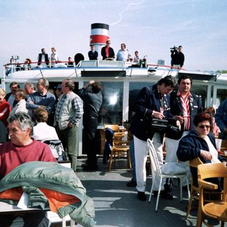 Boat party with people dining outdoors.