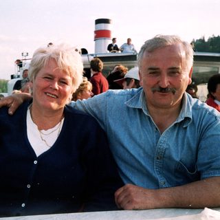 Happy couple posing on a boat by water.