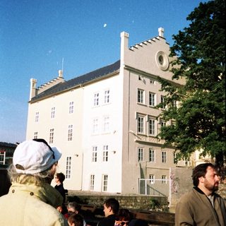 Large historic building with people gathered outside.