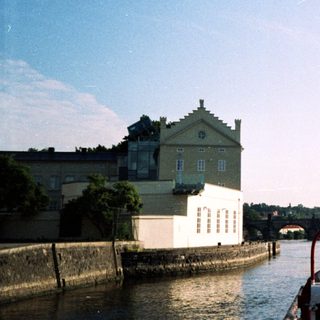 Scenic river view with boat, historic building, bridge.