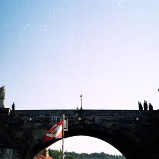 Historic stone bridge with statues and flags.