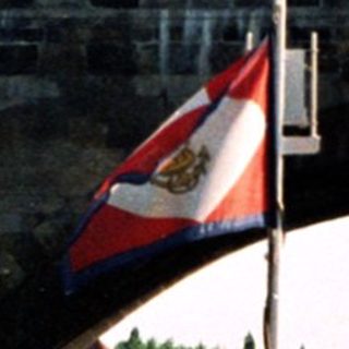 Historic stone bridge with statues and flags.