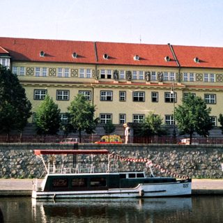 Large riverside building with red roof near boats.