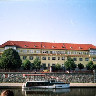 Large riverside building with red roof near boats.
