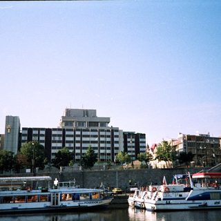 Riverfront scene with boats, modern buildings, and historic architecture.