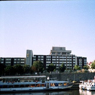 Riverfront scene with boats, modern buildings, and historic architecture.